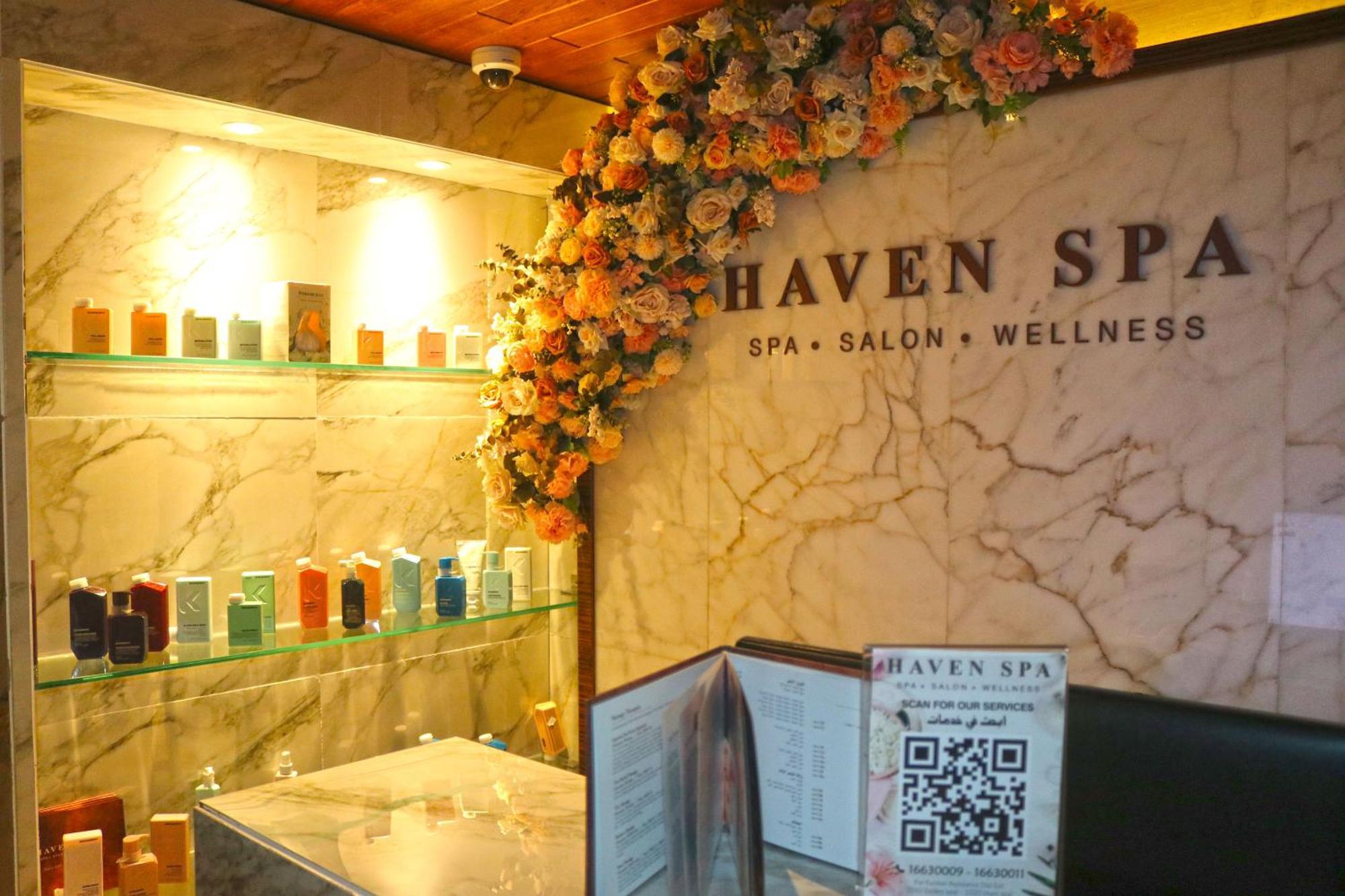Lagoona Beach Luxury Resort And Spa Al-Manamah Bagian luar foto The photo shows the interior of a spa called "Haven Spa." The wall is decorated with beautiful artificial flowers, creating an inviting atmosphere. There are several shelves displaying various colorful bottles and products, likely for skincare or wel