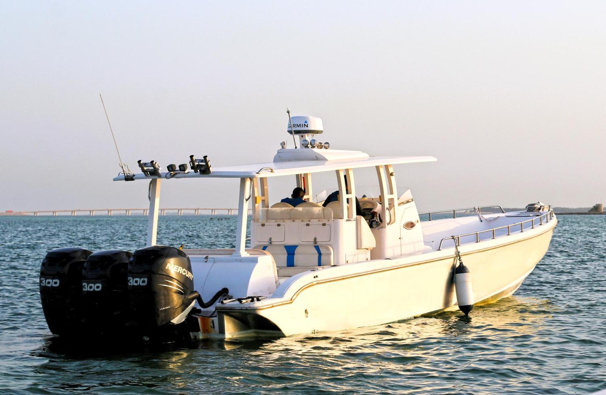 Lagoona Beach Luxury Resort And Spa Al-Manamah Bagian luar foto The photo shows a large, white motorboat equipped with three powerful outboard engines at the stern. The boat has a sleek design, with a spacious open deck and a covered cabin area that likely provides shelter and controls for navigation. The scene i